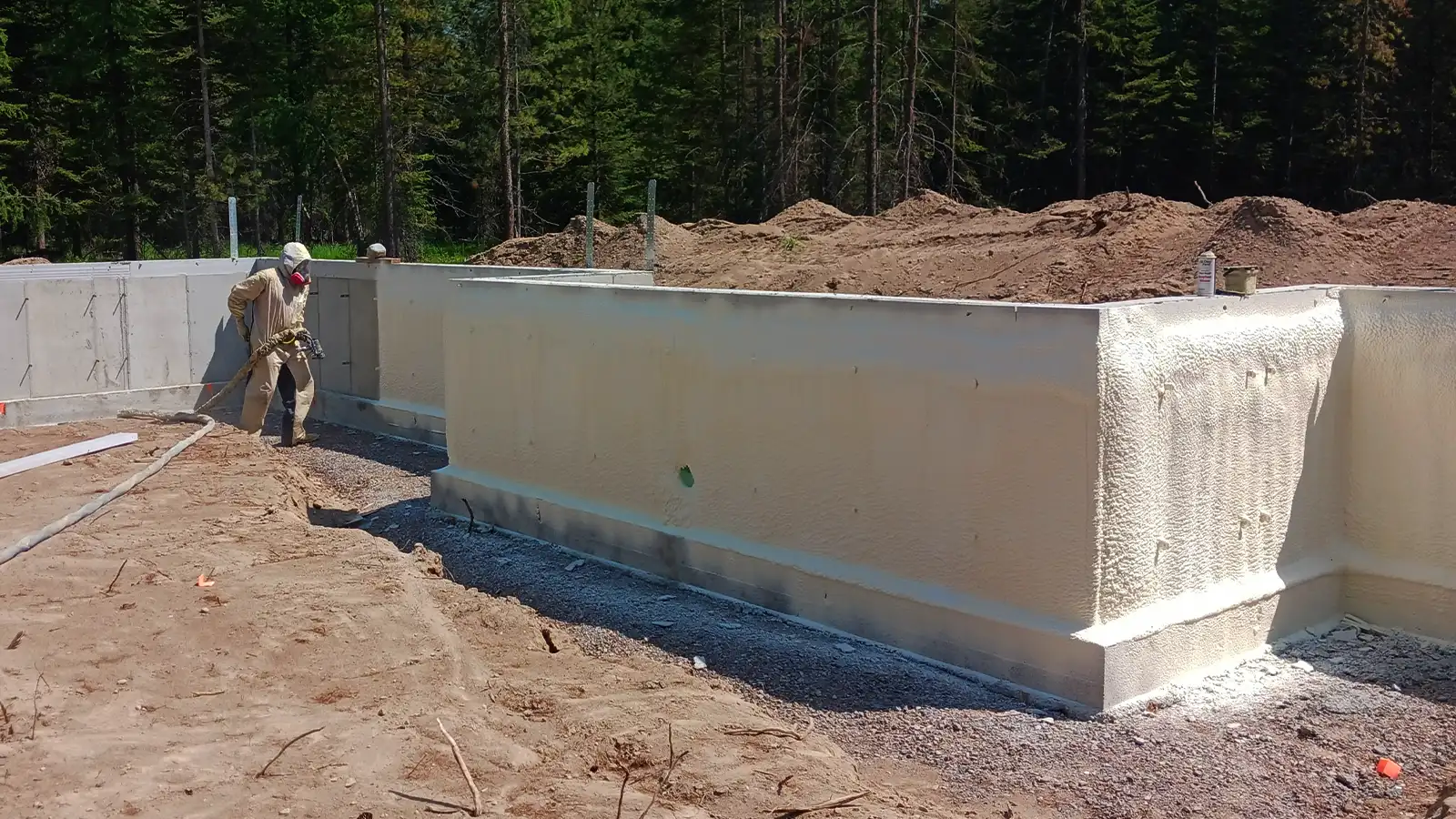 True North insulation installer applying spray foam to an exterior concrete foundation wall